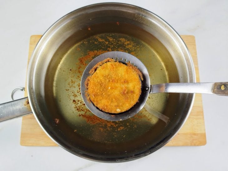 Uma panela com óleo e as rodelas de berinjela a fritar.