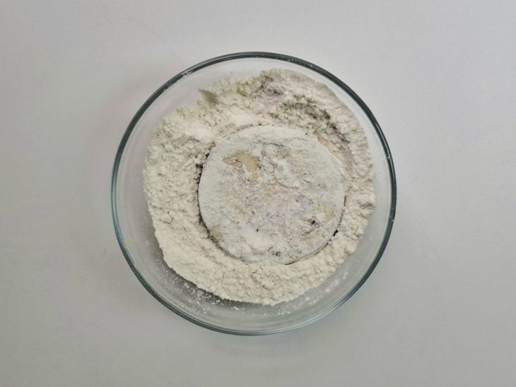 Fatia de berinjela em um pote com farinha.