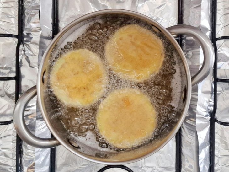 Berinjelas fritando em uma panela com óleo.
