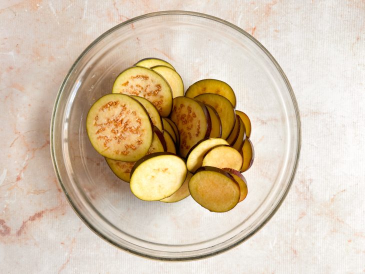 Berinjela lavada e cortada em rodelas médias e uniformes.