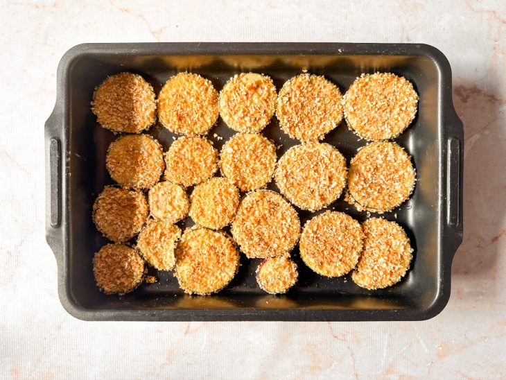 Berinjelas empanadas dispostas na assadeira sem sobrepor.