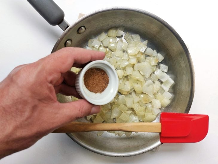 Uma frigideira contendo cebola refogada temperada com pimenta-síria.