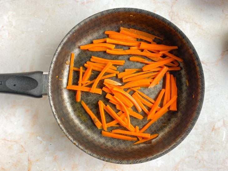 Uma frigideira com a cenoura refogando.