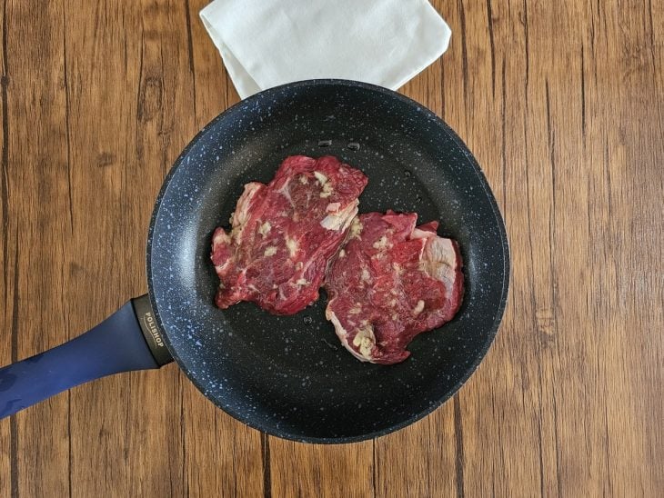 Uma frigideira fritando os bifes.