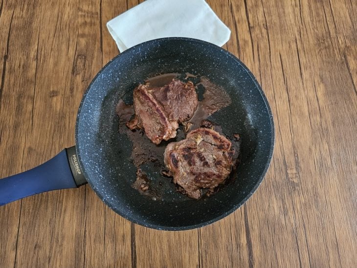 Uma frigideira fritando os bifes.