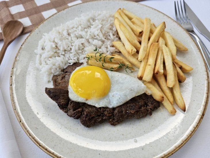 Um prato contendo bife a cavalo com arroz e fritas.
