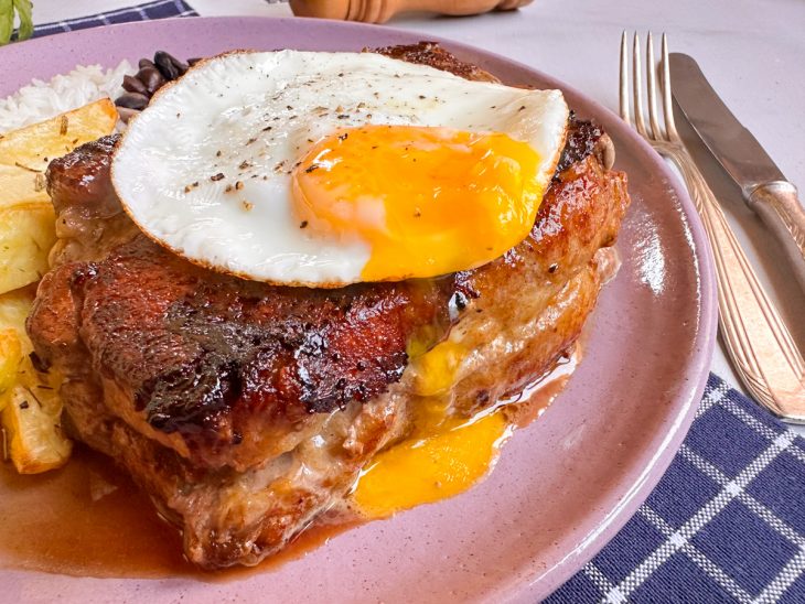 Bife servido com o ovo por cima, num prato individual.