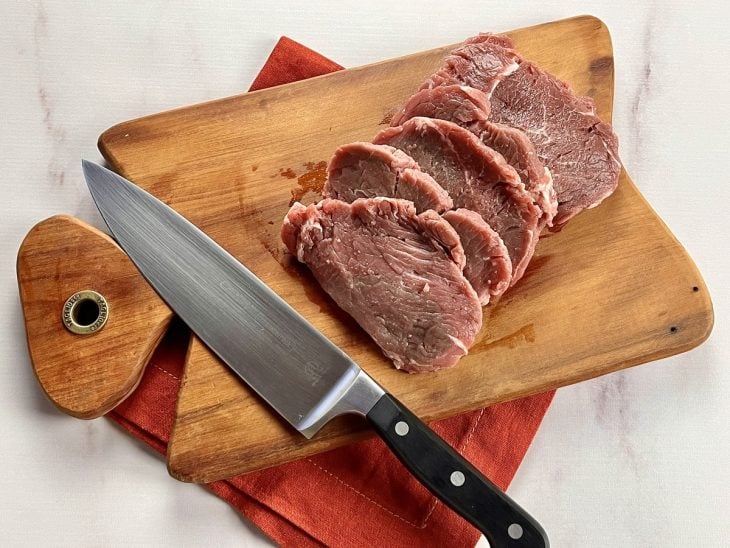 Uma tábua com a carne cortada em bifes.