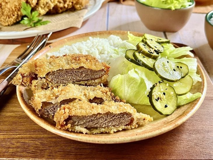 Um prato contendo bifes à milanesa com trigo.