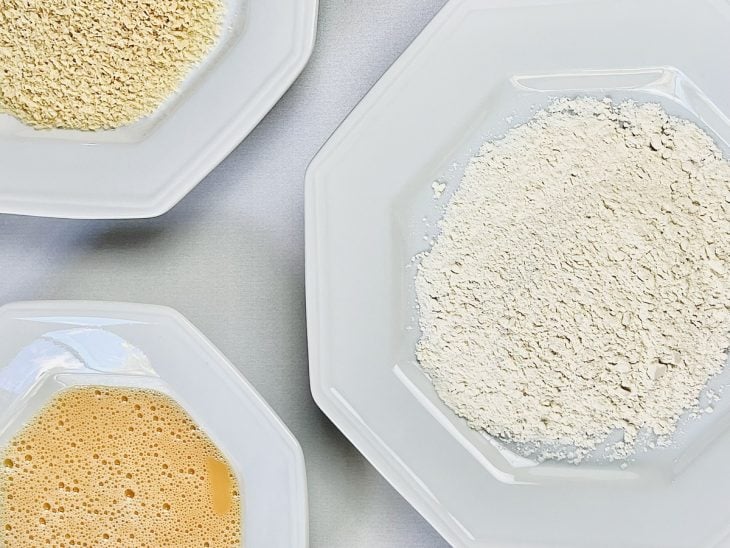 Pratos brancos com farinha de trigo, farinha de rosca e ovos batidos.