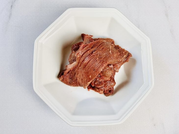 Bifes temperados e reservados em um prato branco.