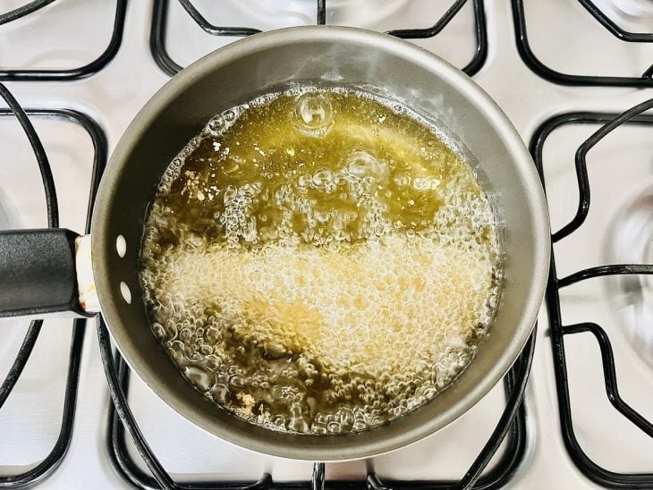 Bife fritando em óleo quente numa panela.
