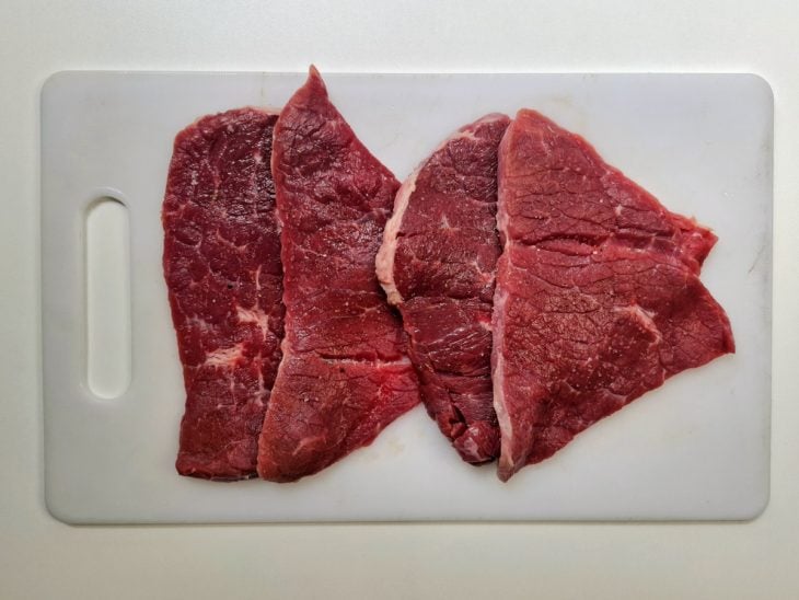 Bifes cortados e temperados em uma tábua.