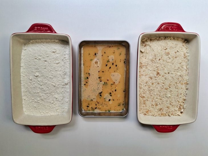 Recipientes com ingredientes para empanar dispostos em uma bancada lado a lado.