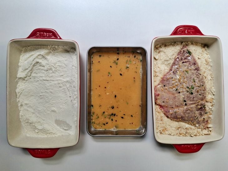 Bife colocado na farinha de pão.