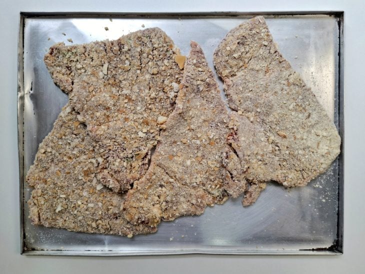 Bifes empanados reservados em uma assadeira.