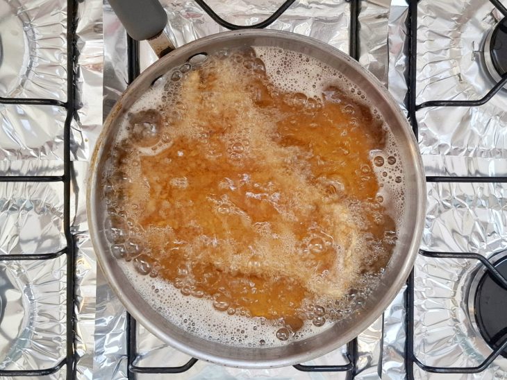 Bifes submersos em óleo para fritar.