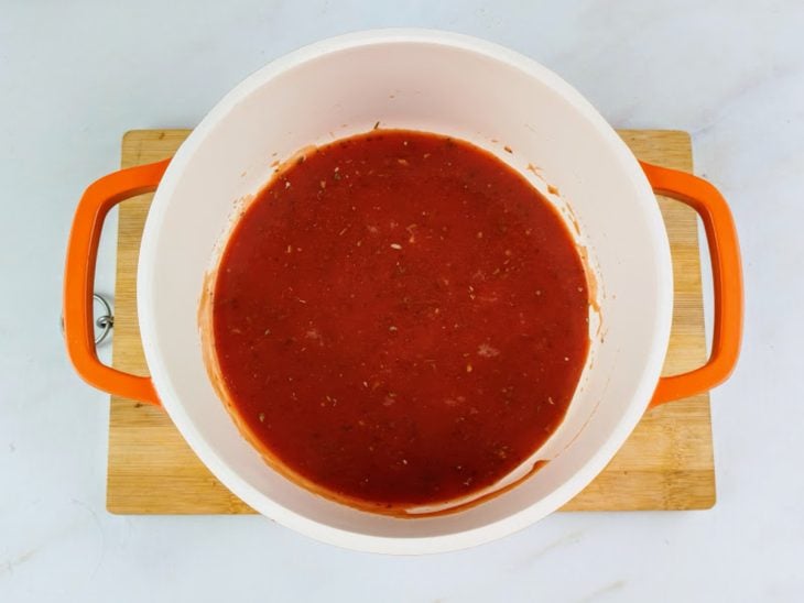 Molho de tomate temperado com sal, pimenta-do-reino e orégano em uma panela.