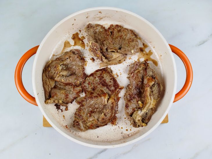 Bifes fritando em uma panela com azeite.