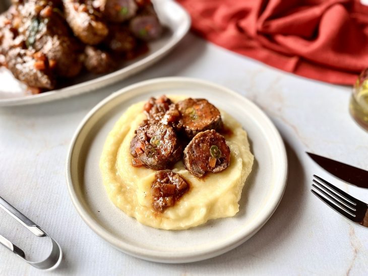 bife a rolê finalizado, cortado e servido com purê de batatas.
