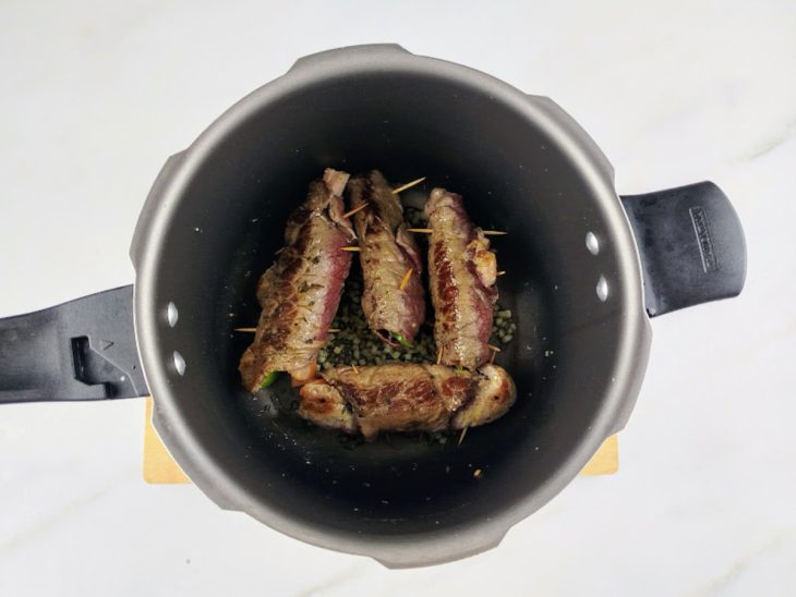 Uma panela de pressão com bifes a dourar.