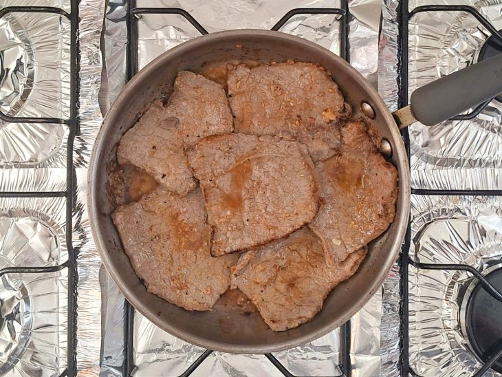 Bifes sendo selados dos dois lados na frigideira.