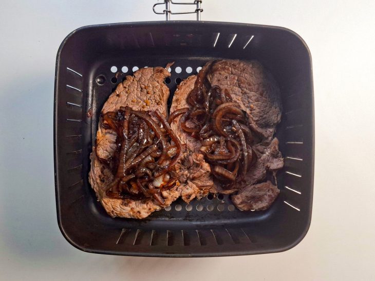 Cebola disposta sobre os bifes na air fryer.