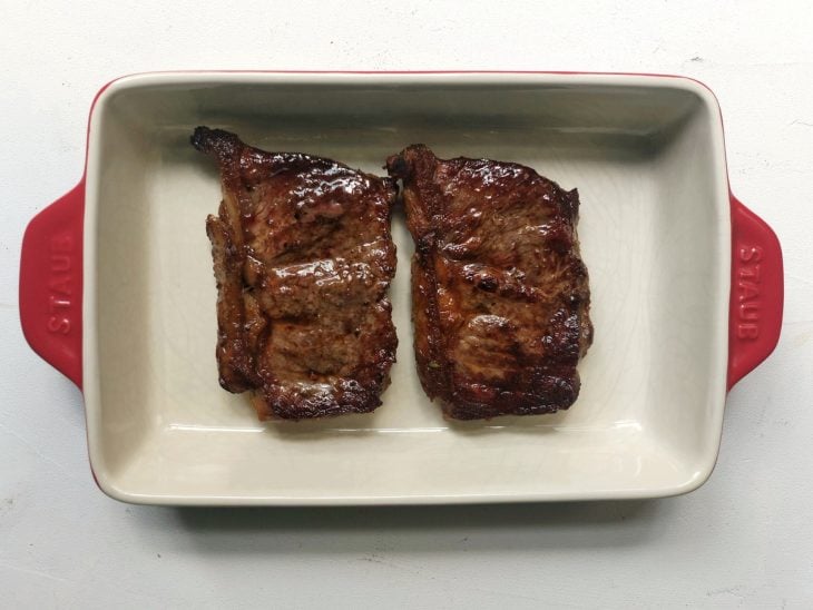 Refratário com dois bifes de chorizo dourados.