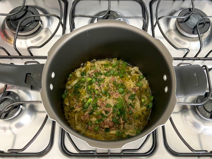 Panela de pressão aberta com os bifes e finalizado com cheiro-verde.