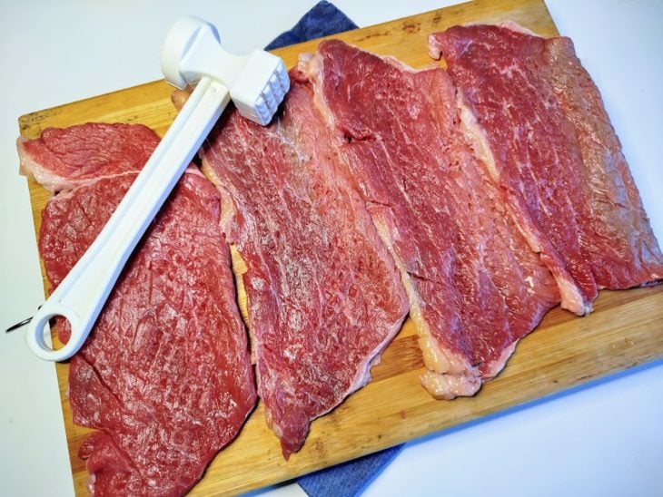Uma tábua contendo bifes de coxão duro crus.