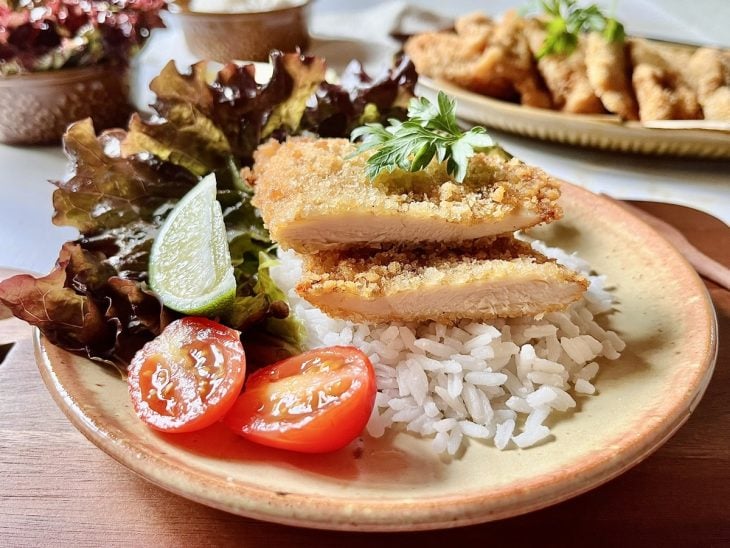 Bife de frango à milanesa servido com arroz e salada.