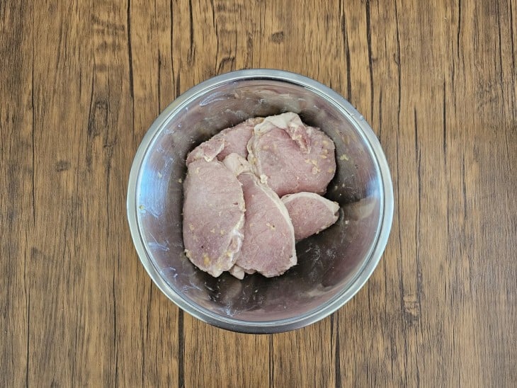 Um recipiente com bife de lombo de porco temperado.