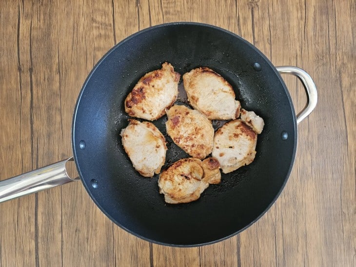 Uma frigideira com bifes de lombo fritos.