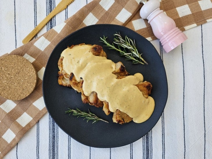 Um prato com bife de lombo de porco com molho.