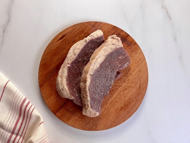 Uma tábua contendo dois bifes de picanha temperados.