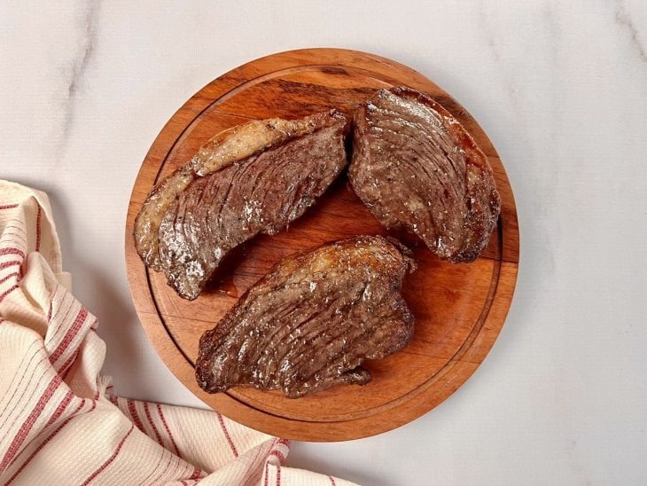 Uma tábua contendo bifes de picanha após fritarem.