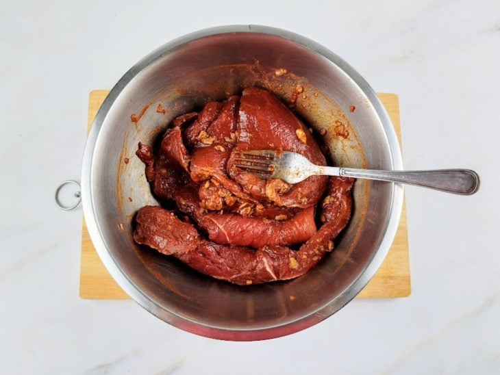 Temperos misturados nos bifes com auxílio de um garfo.
