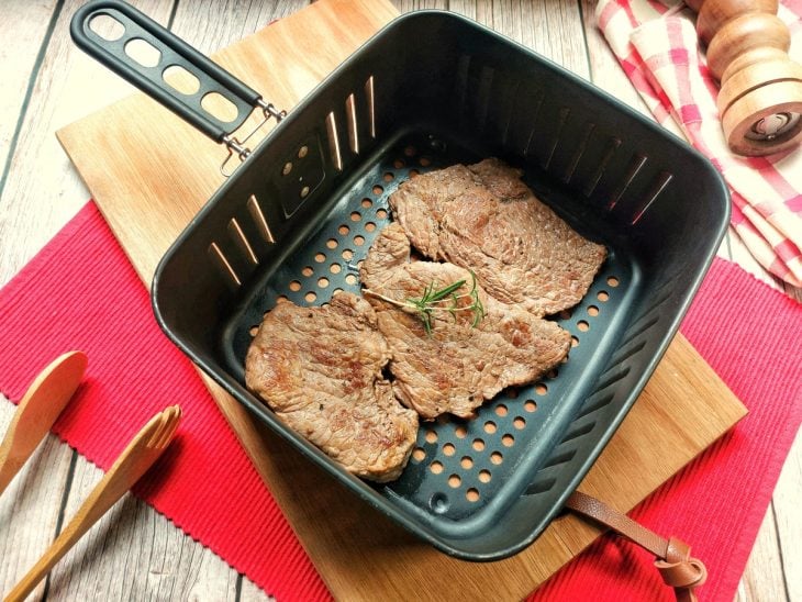 Bifes fritos dentro do cesta da airfryer.