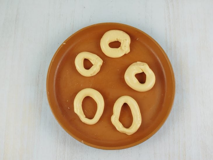 Pequenas porções de massa sendo enroladas e moldadas no formato de rosquinha.