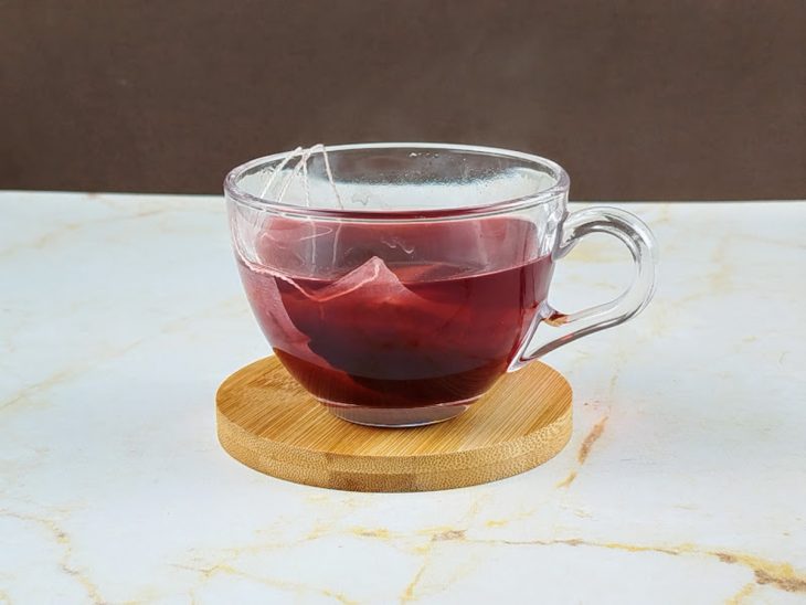 Sachê de chá em infusão em uma xícara de vidro.