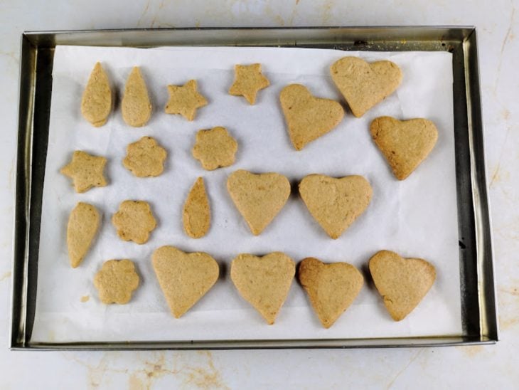 Biscoitos amanteigados assados em uma assadeira forrada com papel-manteiga.