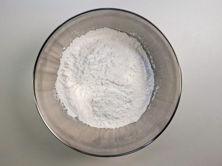 Farinha de araruta sendo peneirada em tigela grande.