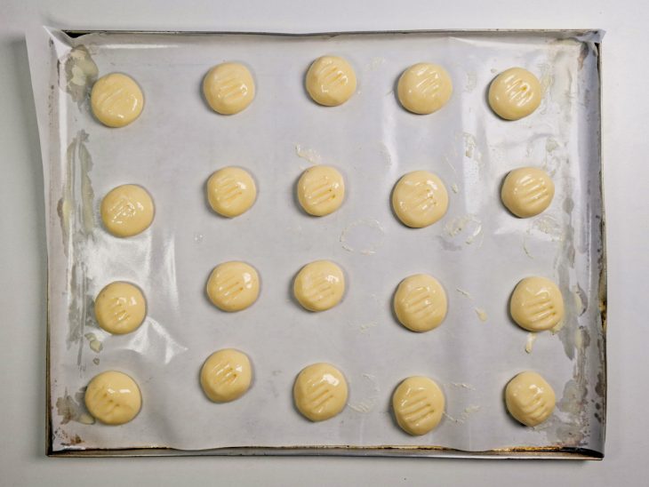 Bolinhas modeladas e distribuídas na assadeira com espaço entre elas.