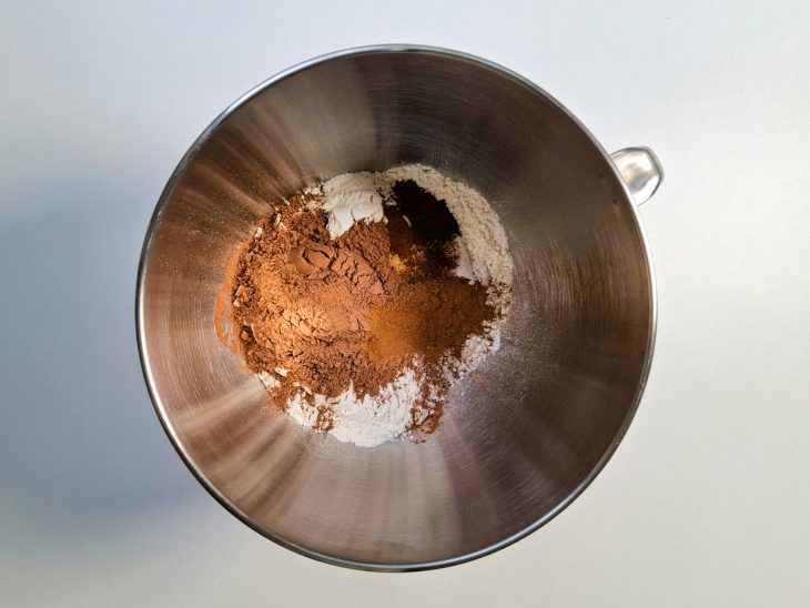 Numa tigela, a farinha de trigo, o sal, o fermento, o gengibre, a canela, o cravo, o cacau e a noz-moscada adicionados.