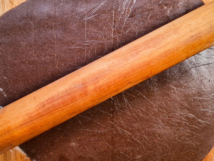 Na bancada, massa aberta com a ajuda de um rolo.