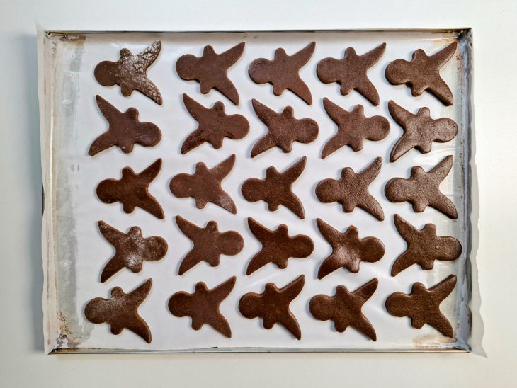 Numa assadeira, biscoito já cortados com o auxílio do molde.