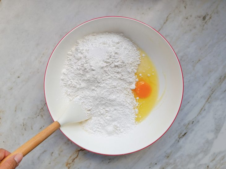 Na tigela, o trigo, o polvilho, o fermento químico e o ovo adicionados.