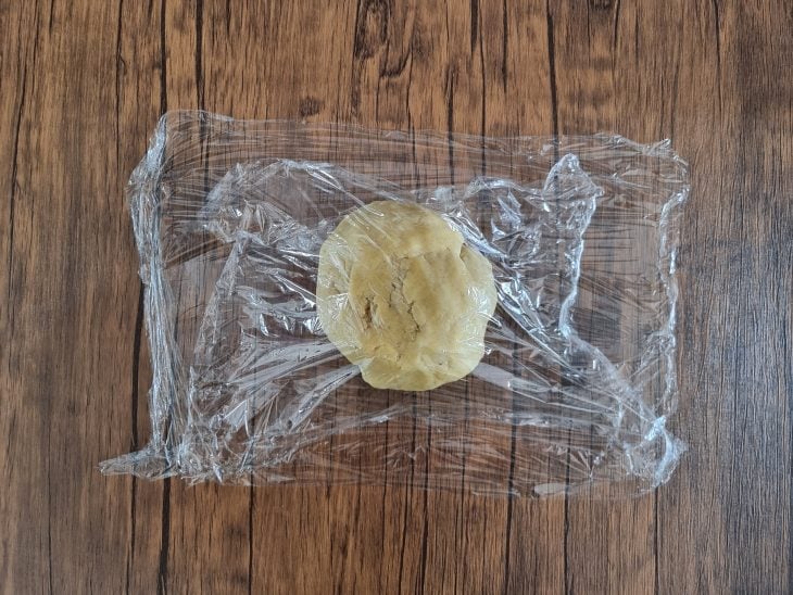 massa do biscoito em formato de bolo coberta por plástico filme.