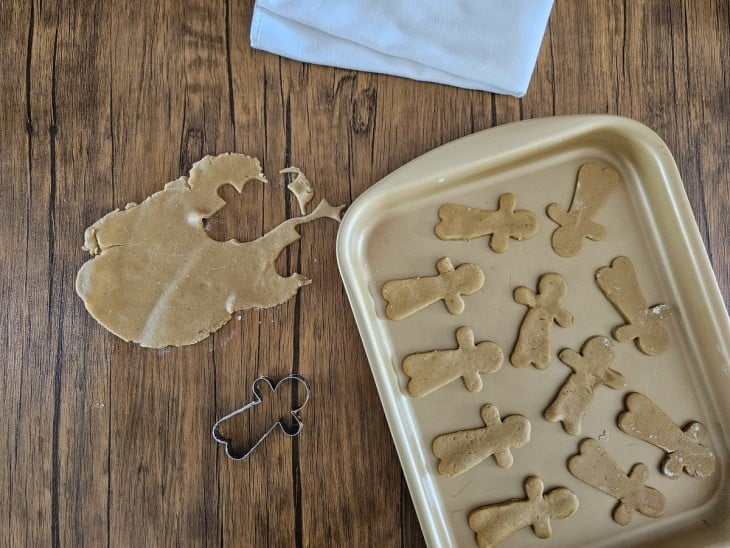 Massa aberta e travessa com alguns biscoitos de Natal cortados.