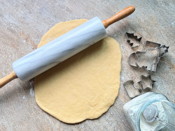 Massa aberta com rolo sobre a bancada enfarinhada.